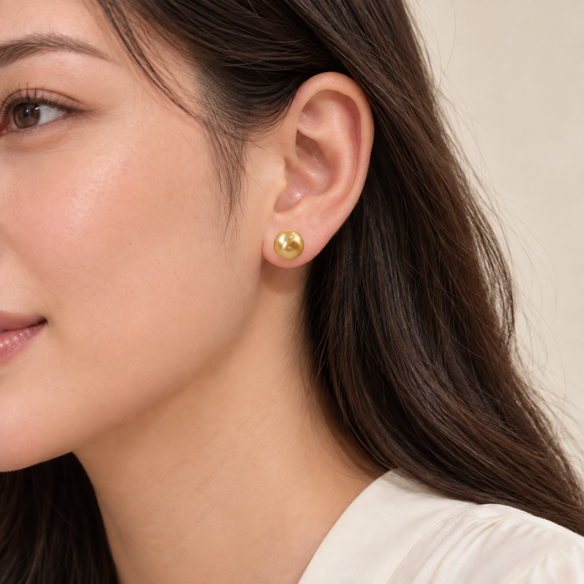 Gold-colored round 10 mm stud earring worn on an ear.