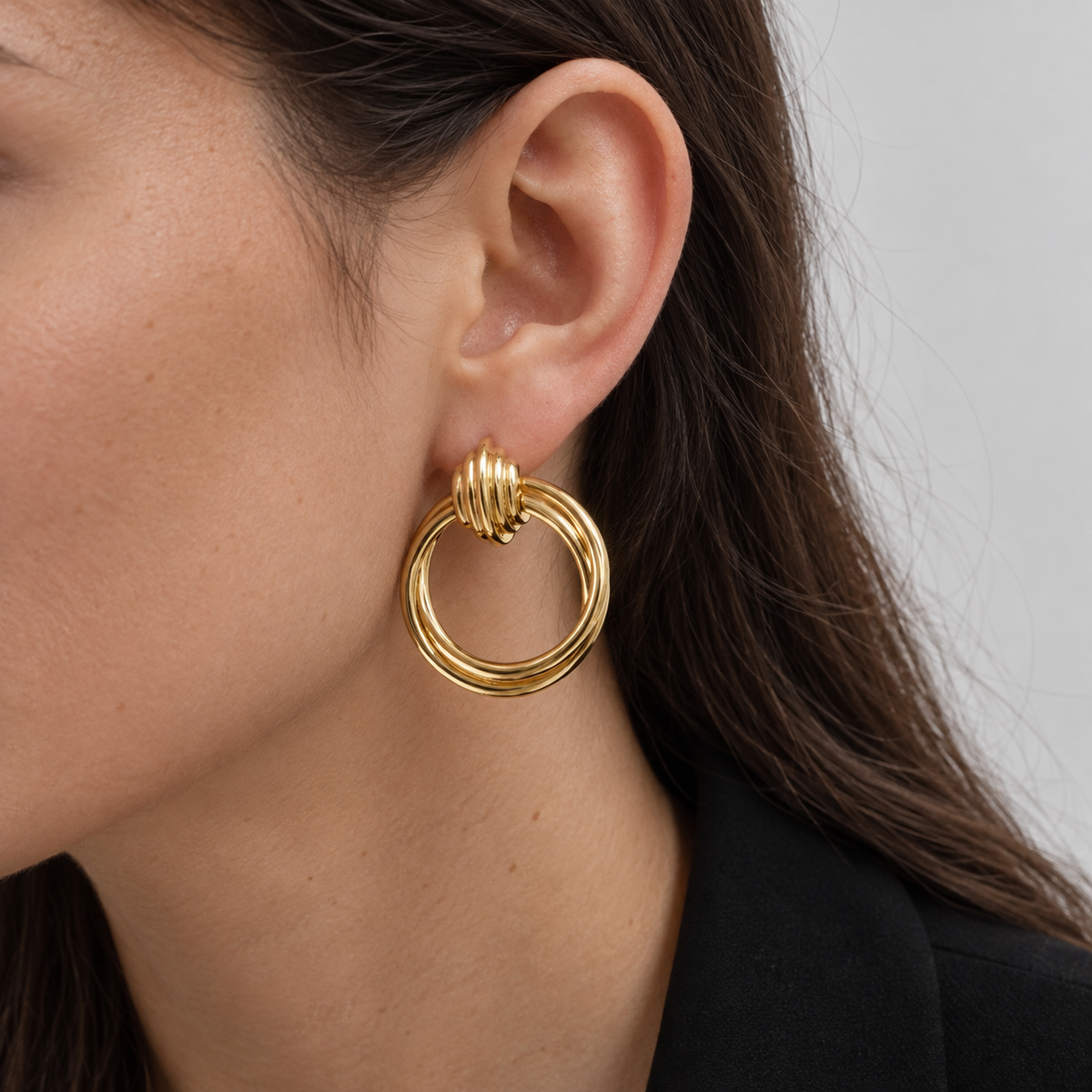 Twisted Soul Gold Hoop Earrings worn on an ear.