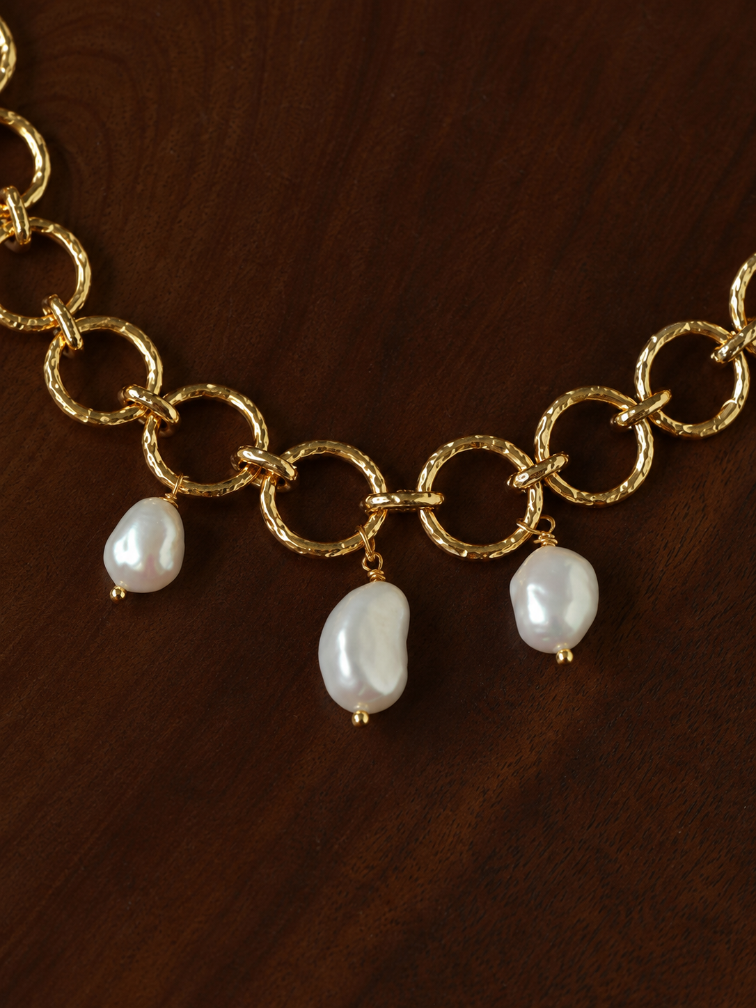 Close-up of the textured gold-tone links and pearl drops.