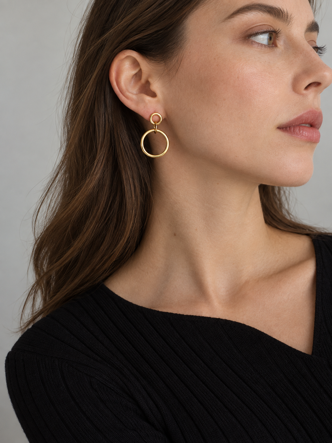 Linked circular gold-tone earrings worn by an adult model.