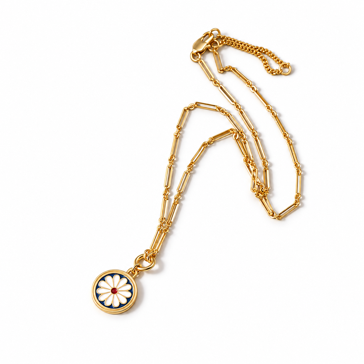 A gold-tone paperclip necklace with a white daisy pendant on a navy disk and red center, arranged on white.
